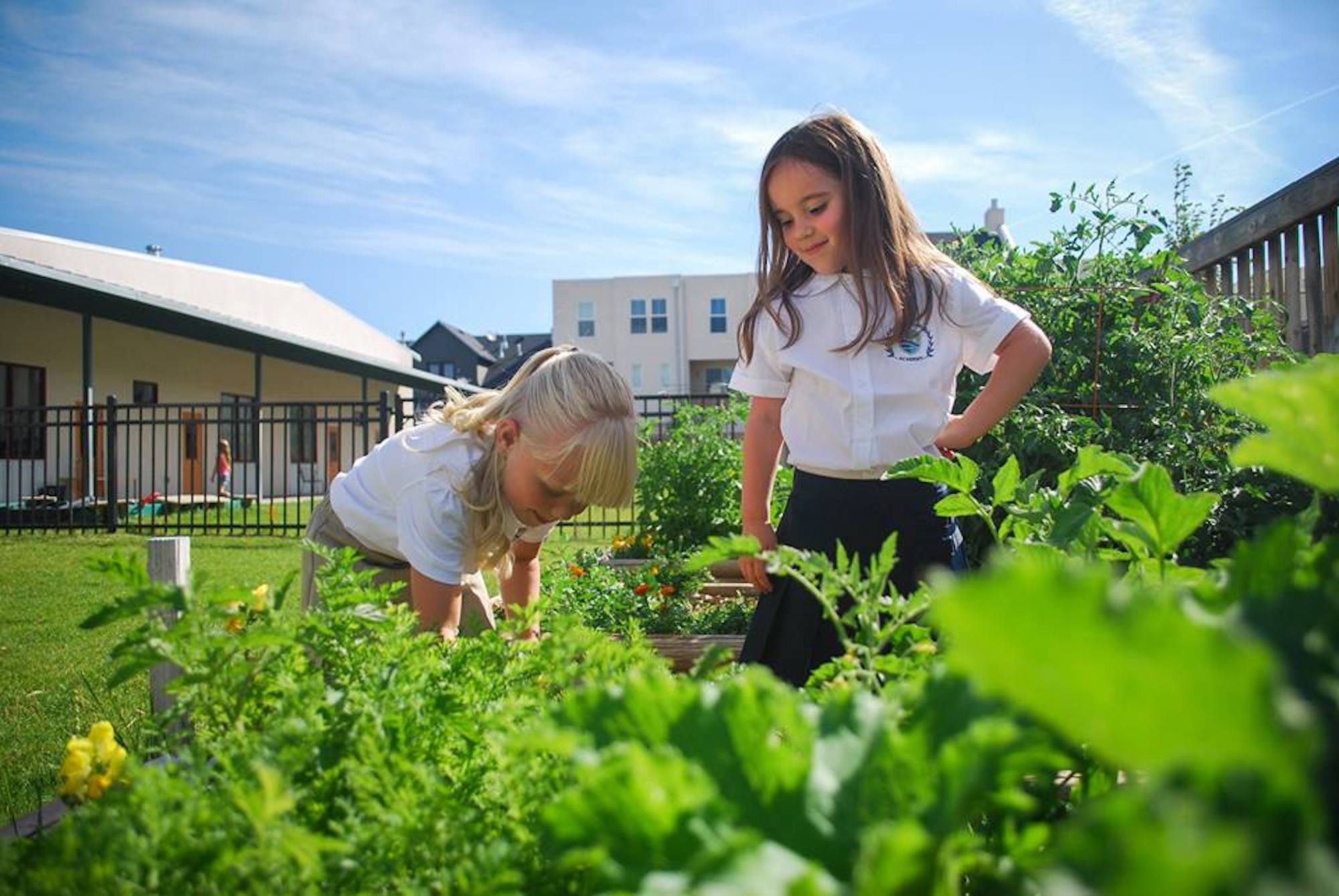 Two young girls in a garden with plants.